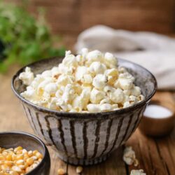 Fluffy buttered popcorn in a rustic bowl on wooden table for movie night or snacks.