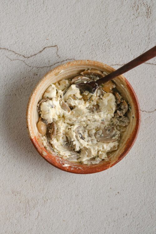 Creamy mushroom dip served in a rustic bowl with a spoon, perfect for appetizer or snack.