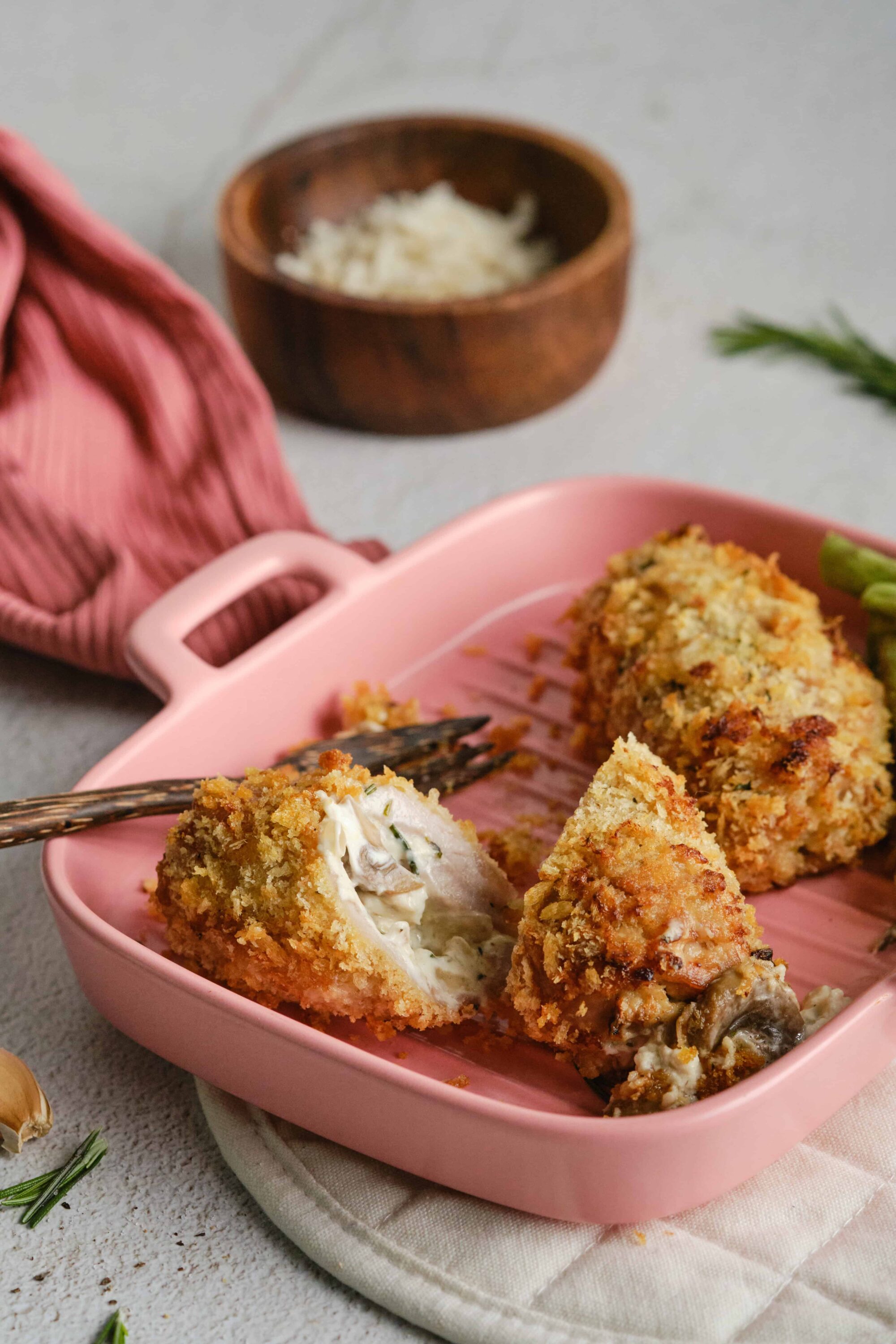 Crunchy stuffed mushroom caps with herbed cream cheese filling on pink baking dish.