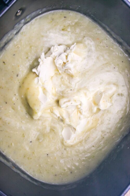 Creamy cheese sauce with softened cream cheese in a saucepan, ready for a comforting recipe.