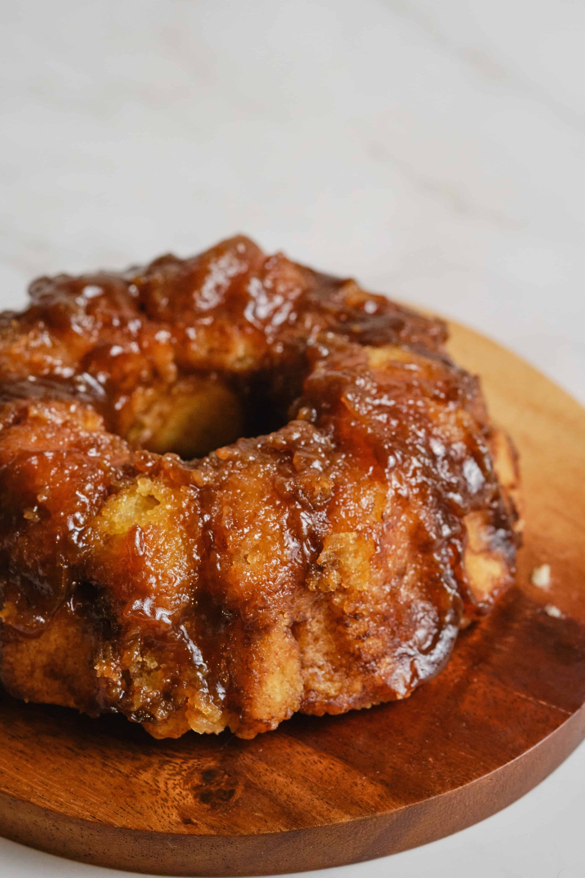 Crispy fried chicken drumstick with rich barbecue glaze on wooden plate.