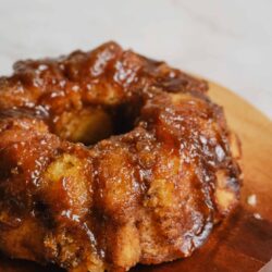 Crispy fried chicken drumstick with rich barbecue glaze on wooden plate.