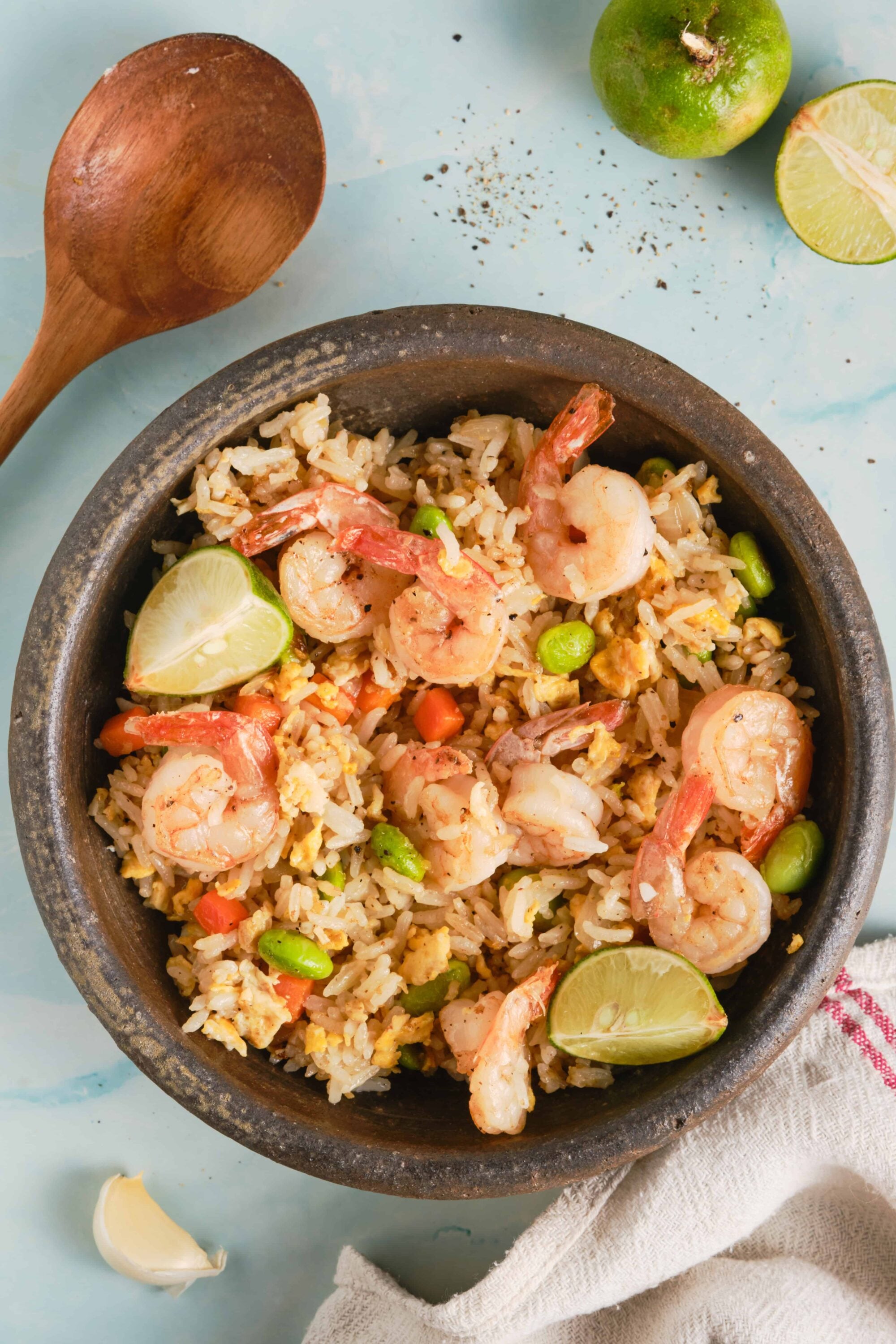 Tender shrimp and vegetable fried rice in a rustic bowl, garnished with lime wedges. Perfect for easy, flavorful seafood meals.