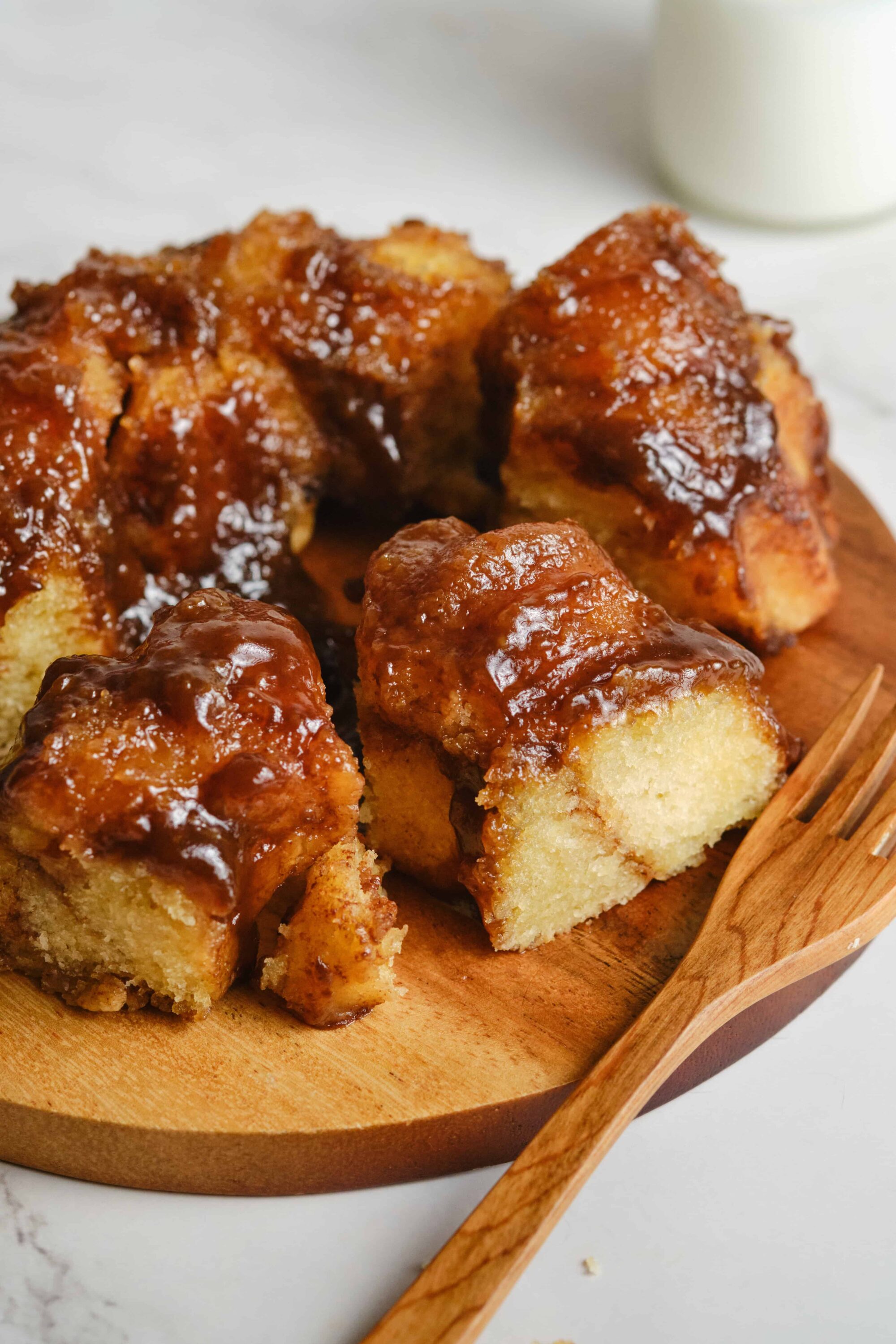 Buttery cinnamon roll cake with caramel glaze on a wooden serving board.