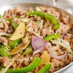 Savory ground turkey stir-fry with bell peppers, onions, and sesame seeds in a white skillet.