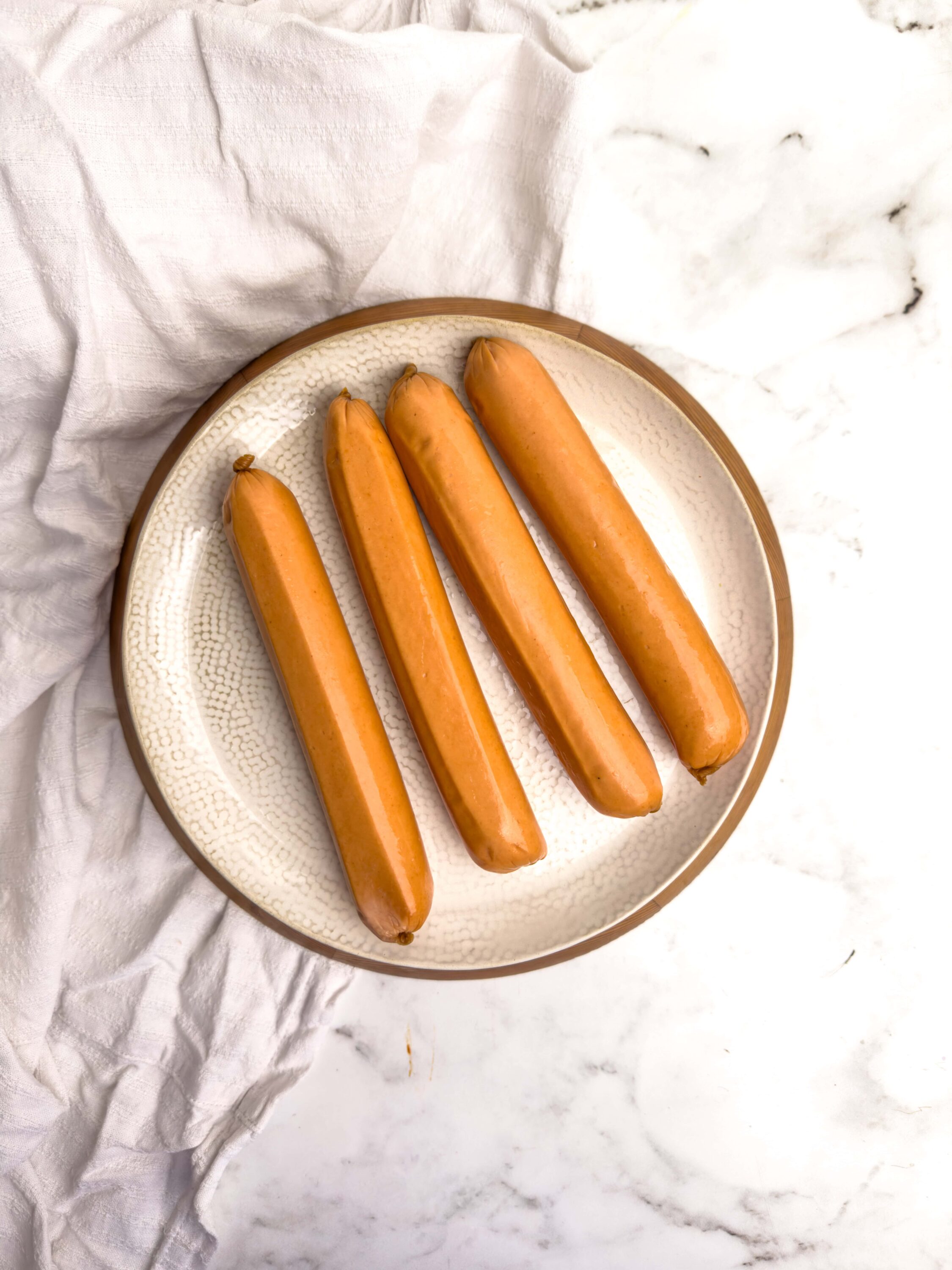 Golden hot dogs on a white plate for easy summer grilling.