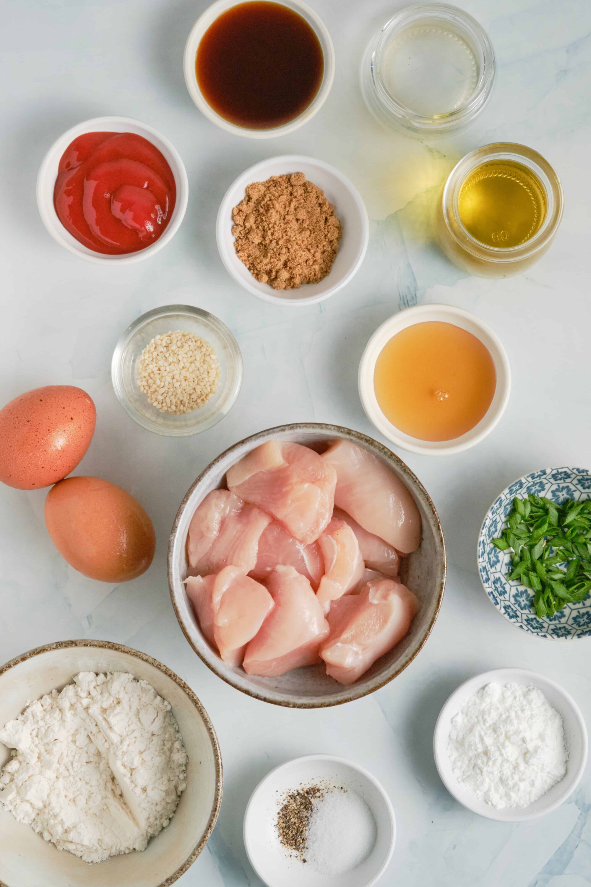Raw chicken and baking ingredients for cooking or baking - eggs, flour, spices, sauces, and herbs.