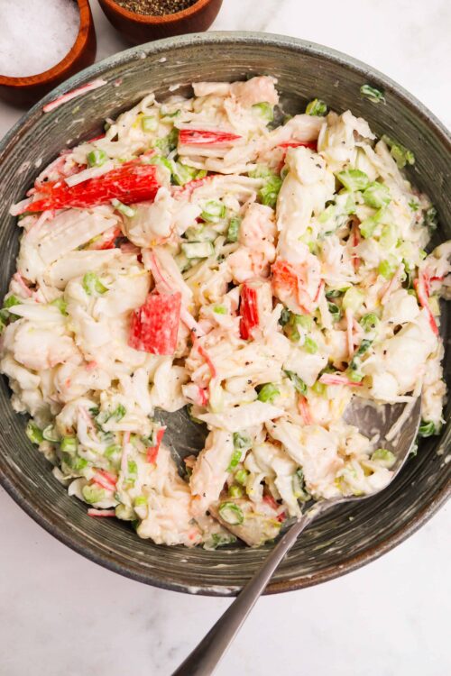 Creamy crab salad with fresh vegetables in a rustic bowl, perfect for seafood and summer recipes.