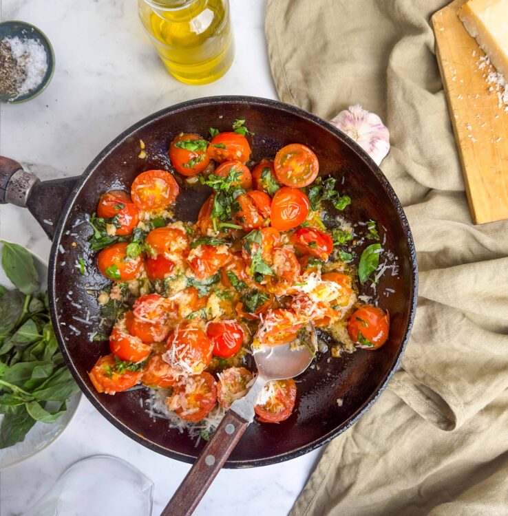 Fresh cherry tomato and garlic sauté in a skillet with basil and parmesan cheese, perfect for a quick pasta dish.