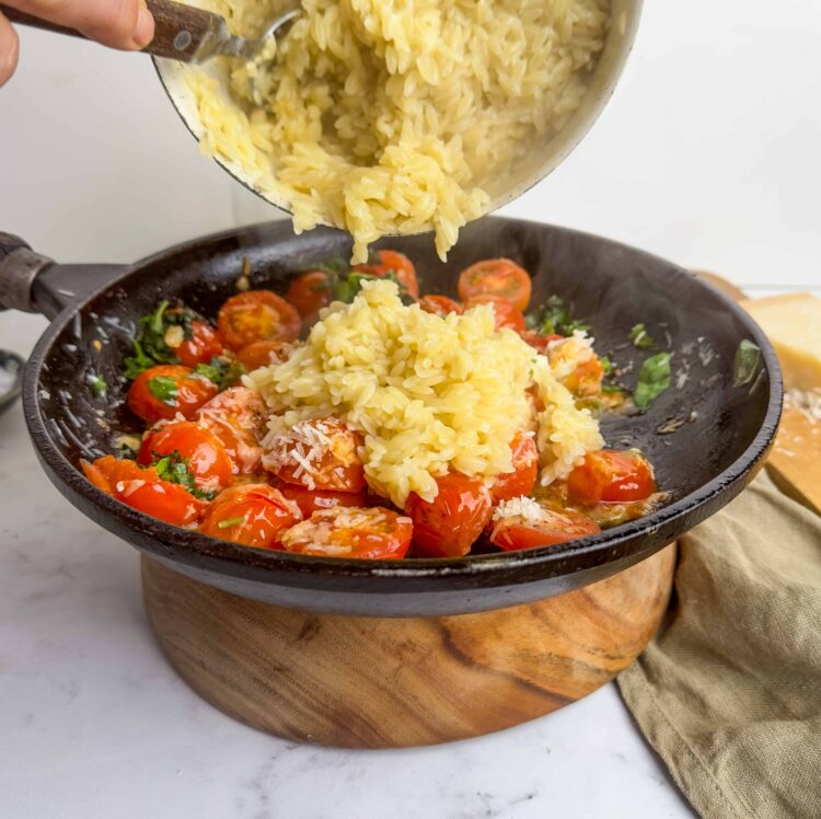 Creamy risotto with cherry tomatoes and fresh herbs in a black skillet.