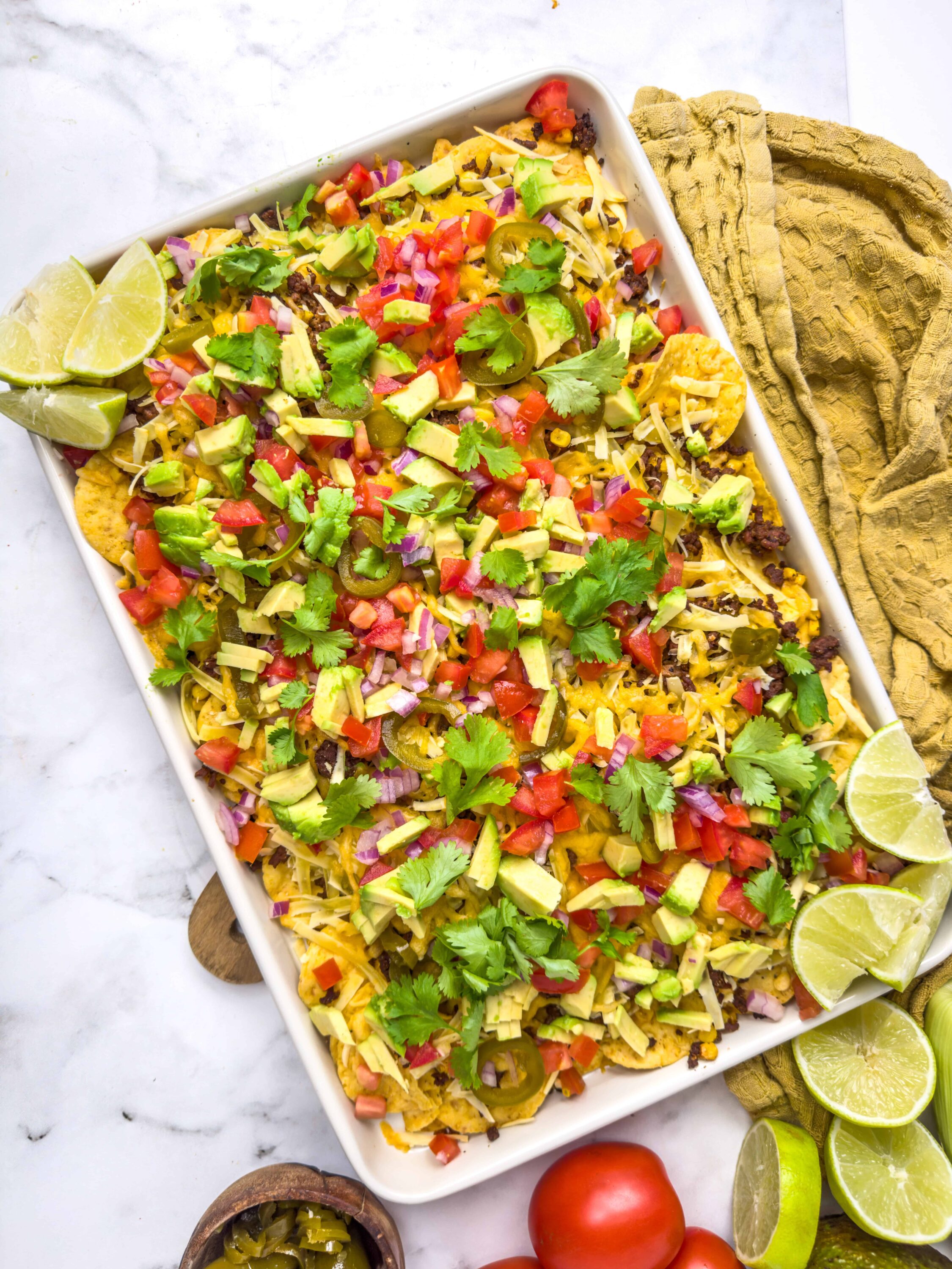 Colorful loaded nachos with fresh avocado, tomatoes, cilantro, and lime wedges. Perfect for party snacks or a quick Mexican meal.