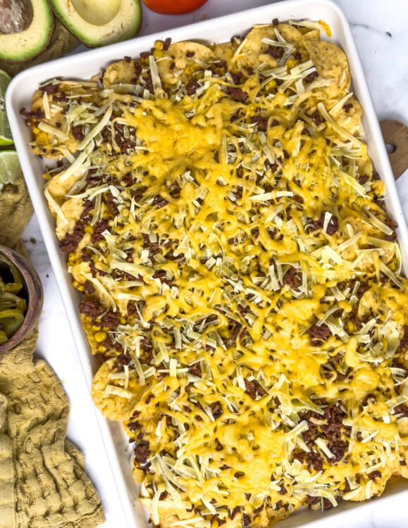 Cheesy taco casserole in a white baking dish with shredded cheese and seasoned beef.
