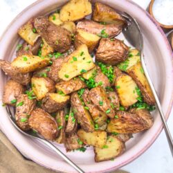 Roasted potatoes with herbs in a pink ceramic bowl, crispy and golden, perfect for comfort food recipes.