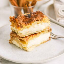 Buttery homemade cream pie with a golden flaky crust and creamy filling on a white plate.