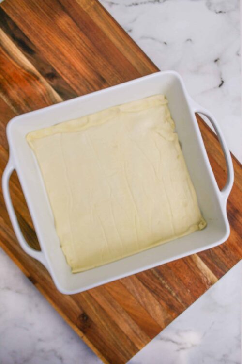 Thin, uncooked pastry crust in a white baking dish ready for baking.