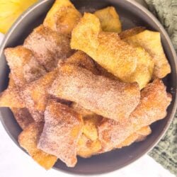 Golden crispy homemade churros dusted with cinnamon sugar in a dark bowl. Perfect for tasty dessert or snack.