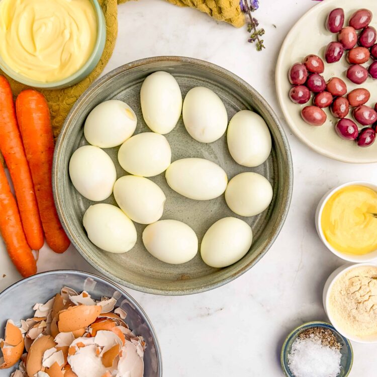 Boiled eggs with fresh vegetables, mayonnaise, and seasonings on a light background.