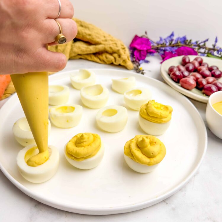 Creamy stuffed eggs with bright yellow filling on a white platter, perfect for appetizers or brunch.