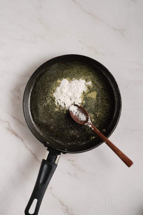 Cream and flour being added to a skillet for baking or cooking.