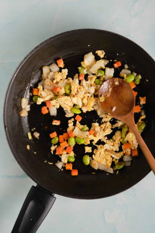 Fried egg mixture with diced vegetables in a black skillet, ready for breakfast or brunch.