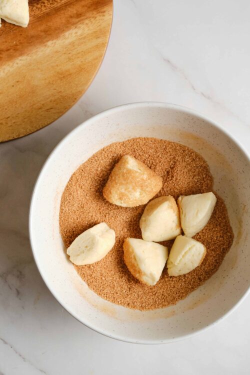 Buttermilk biscuits in sugar mixture, baking ingredients, homemade biscuit preparation, baking process, baked goods.