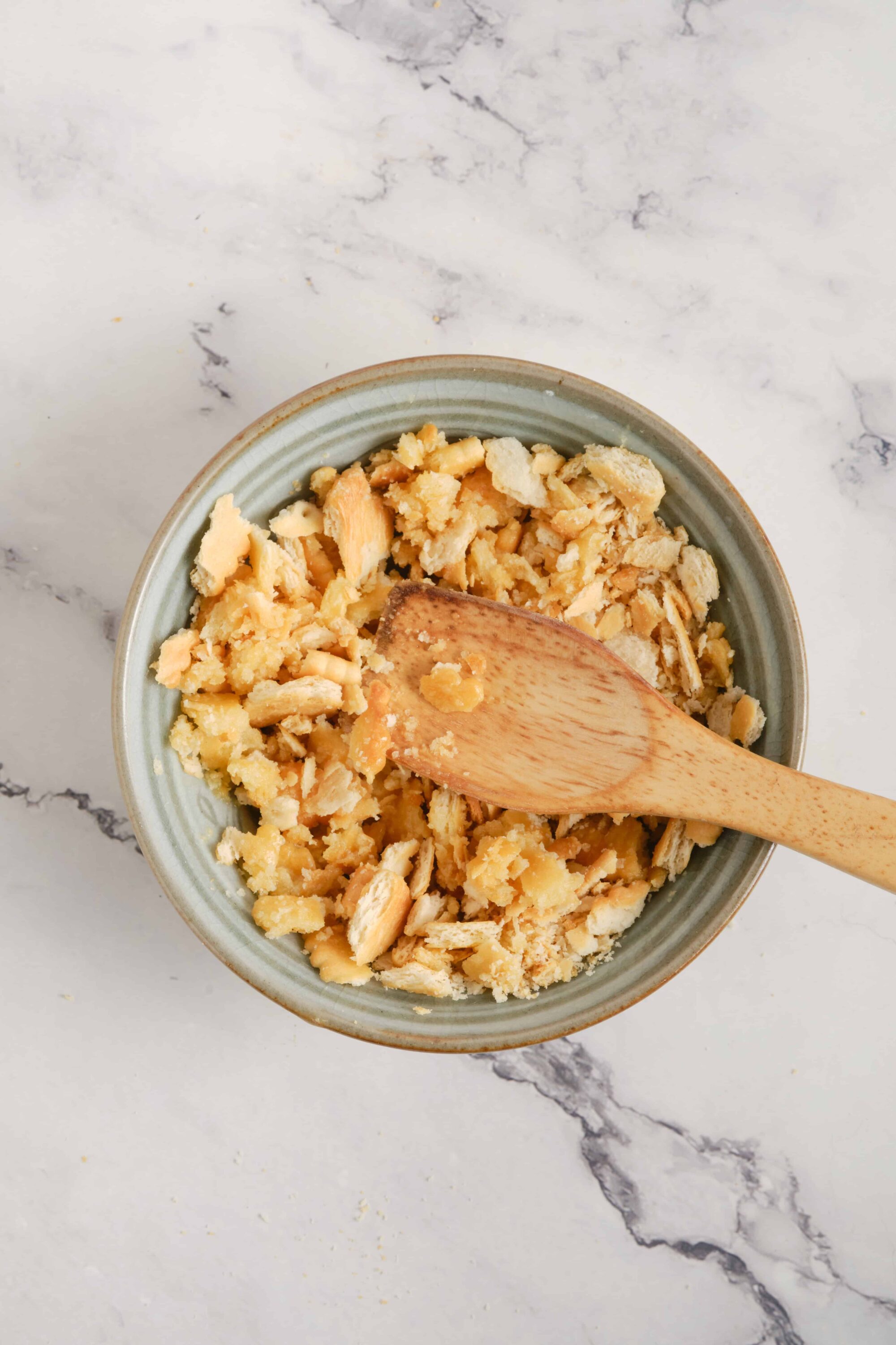Butter crumble in a bowl with a wooden spoon on marble surface, baking and pie crust topping, homemade baking ingredients, close-up of crumbly dough, food preparation.