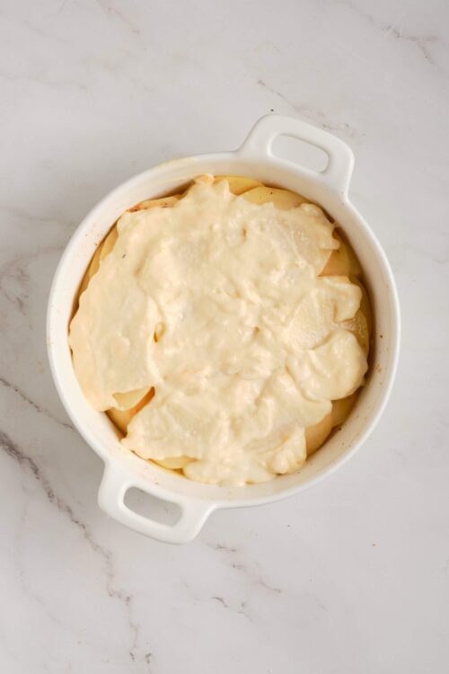 Creamy potato gratin in a white baking dish, ready to bake or serve.