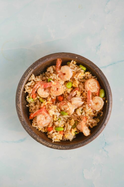Flavorful shrimp fried rice with vegetables in a dark bowl, served as a delicious Asian-inspired meal.