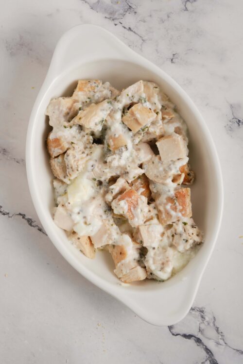 Creamy chicken and mushroom casserole in white dish, baked with cheese and herbs.