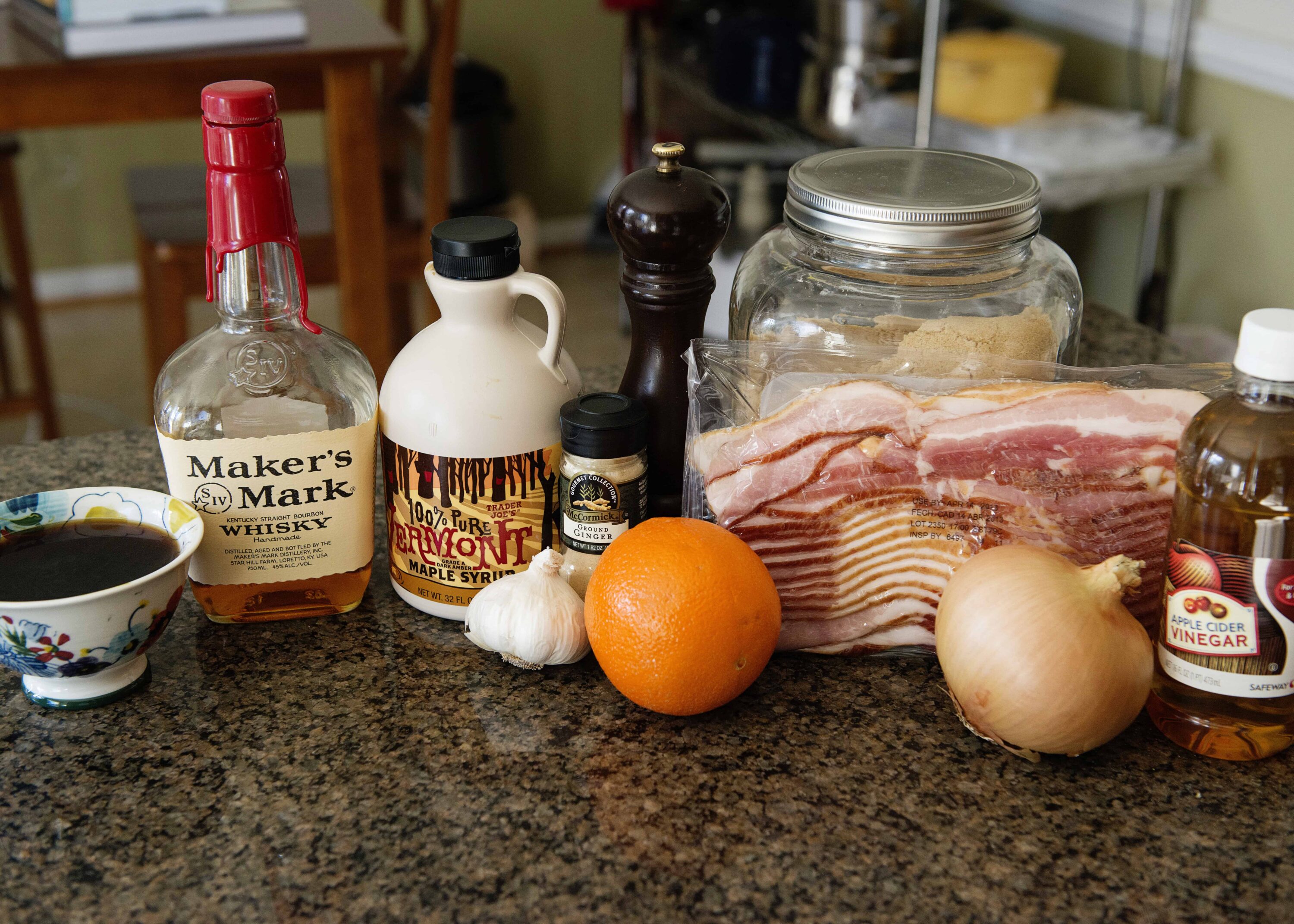 Bottle of bourbon whiskey and ingredients for a savory dish on a kitchen countertop.
