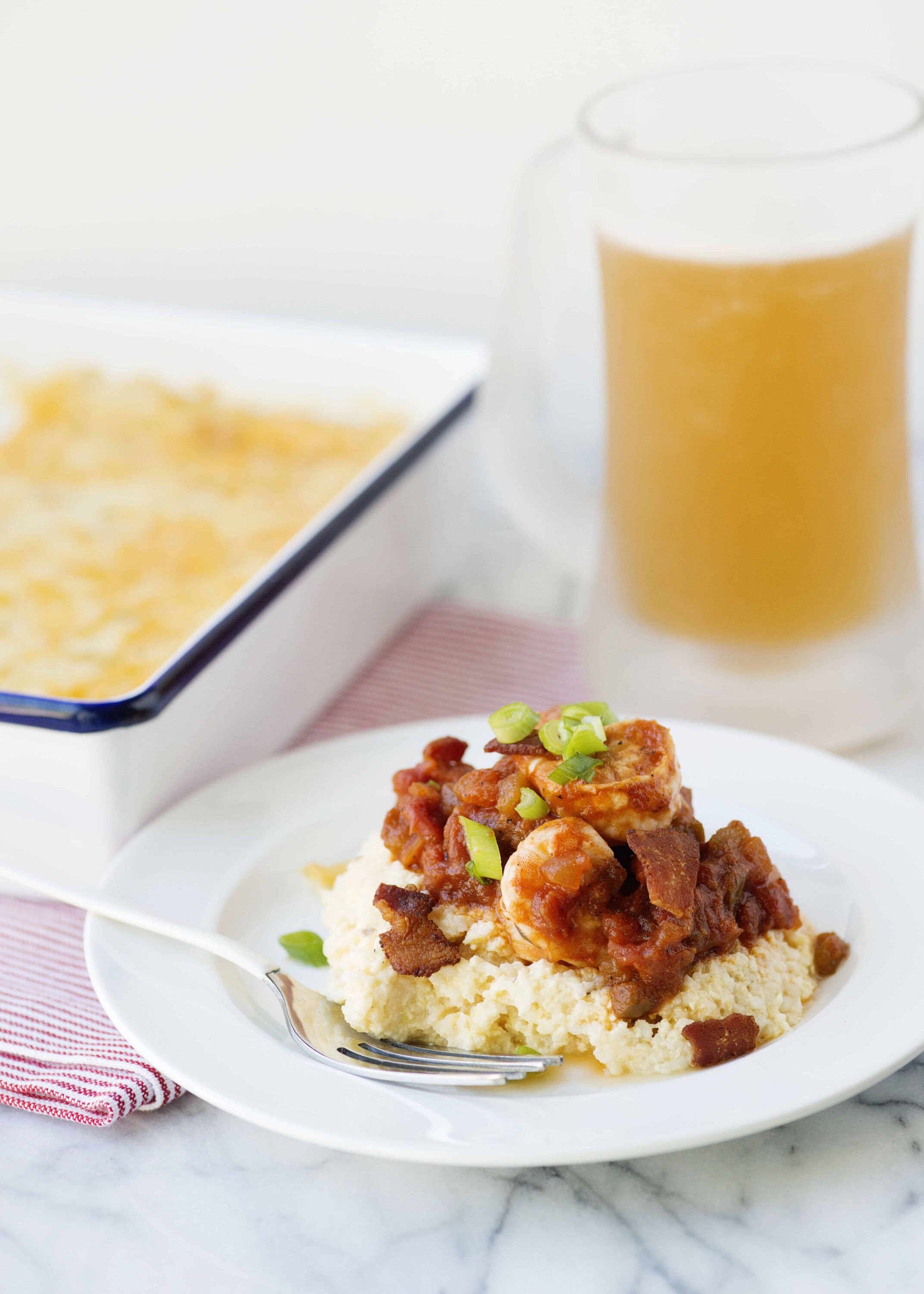 Creamy mashed potatoes with hearty beef stew and green onions on a white plate.