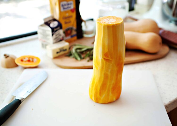 Yellow butternut squash on a white cutting board.