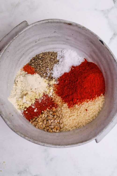 Spice mixture for baking in a white bowl, chili powder and herbs, baking ingredients, close-up.