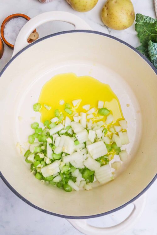 Diced leeks and butter melting in a white Dutch oven for cooking.