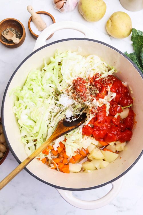 Sautéed vegetables and tomatoes in a pot ready for a baked Bree recipe.