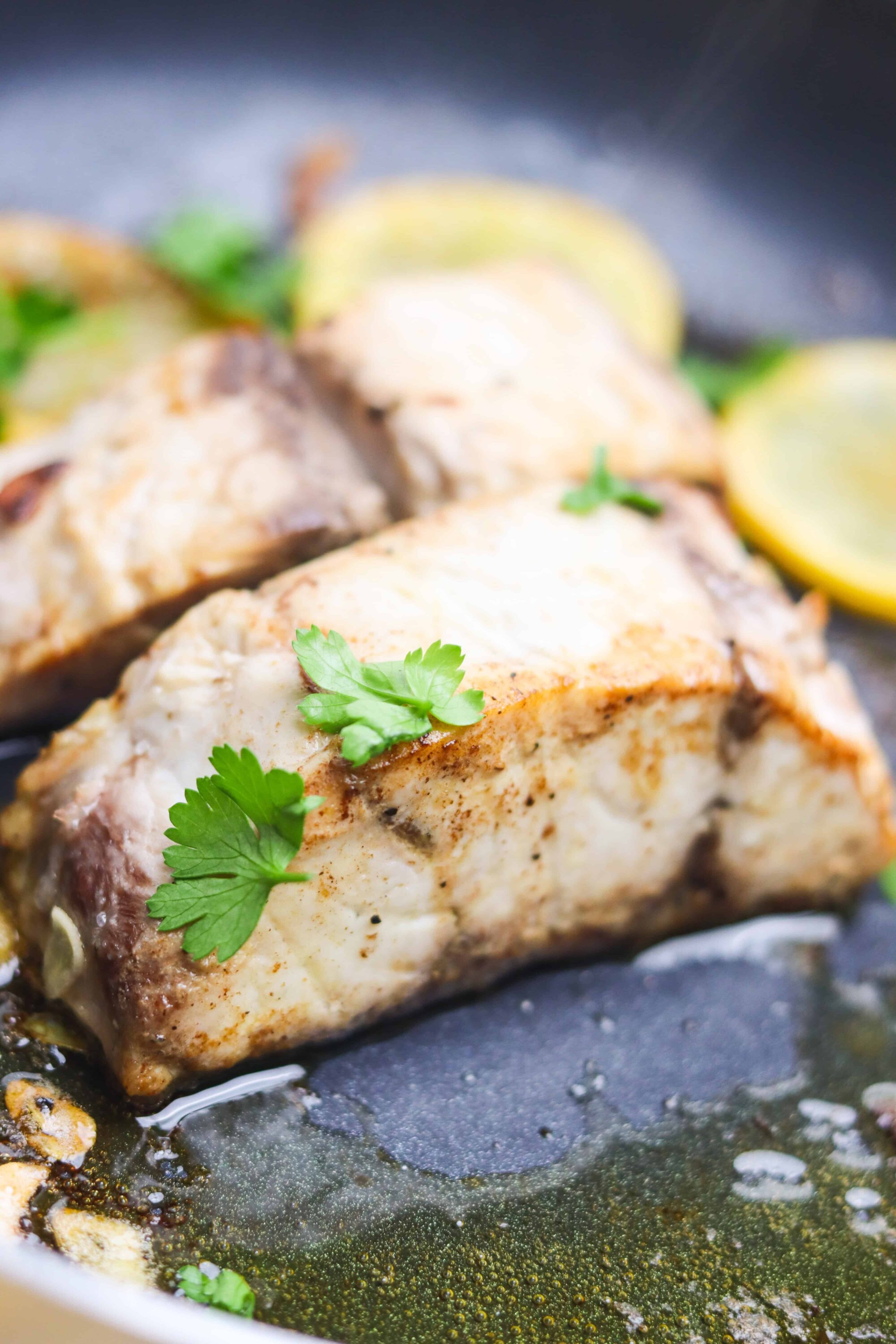 Juicy baked chicken breast with herbs and lemon slices, garnished with cilantro.