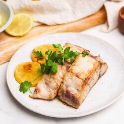 Juicy roasted fish fillet garnished with fresh herbs and lemon slices, perfect for healthy seafood recipes.