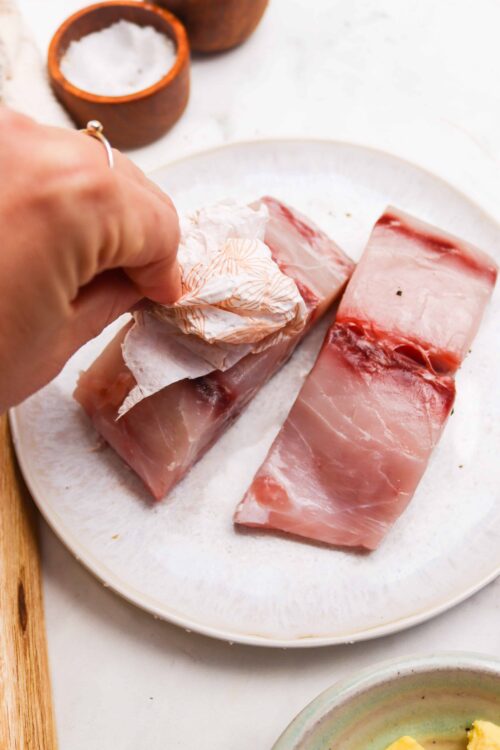 Succulent raw pork loin on a white plate, seasoned and ready for cooking.