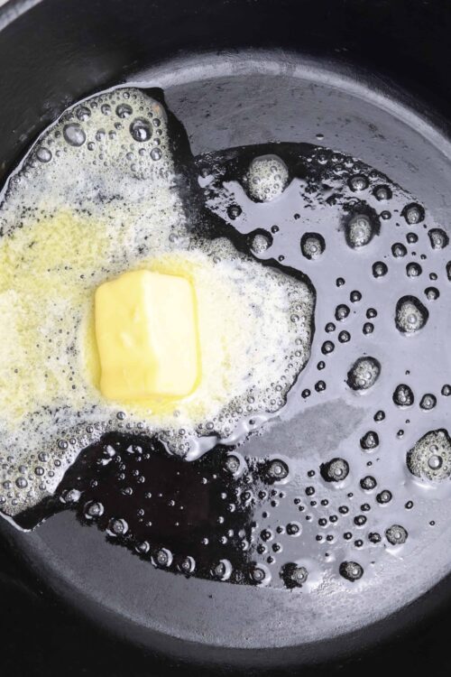Melting butter in a black skillet for baking or cooking.