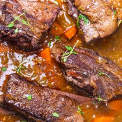 Braised beef short ribs with vegetables and herbs in a savory sauce.