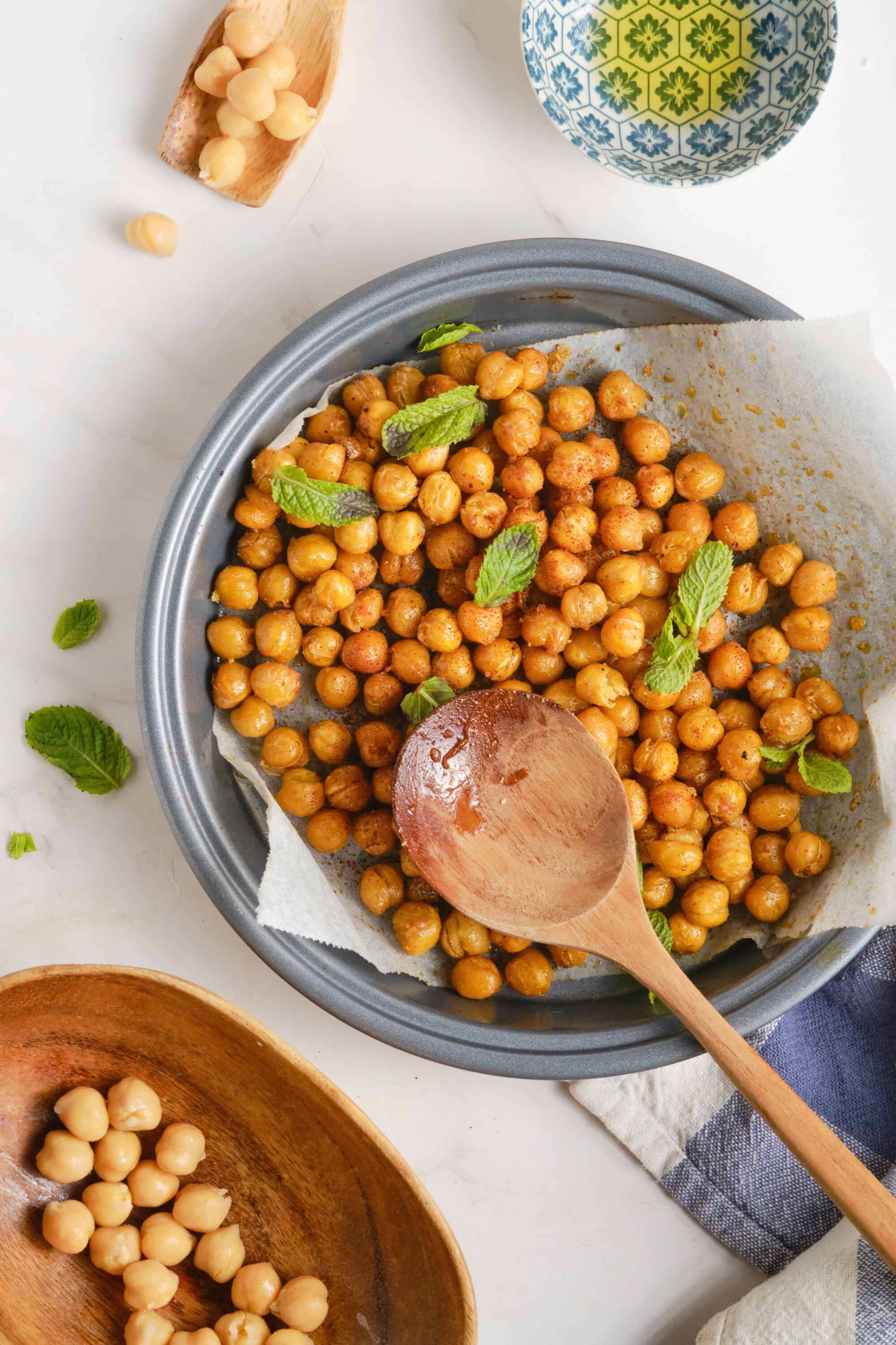 Soft roasted chickpeas garnished with fresh mint leaves on a baking sheet.