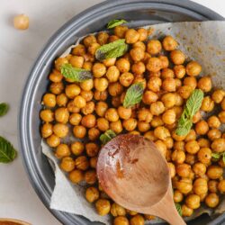 Crispy roasted chickpeas with fresh mint garnish and spices, served in a baking dish for healthy snack.
