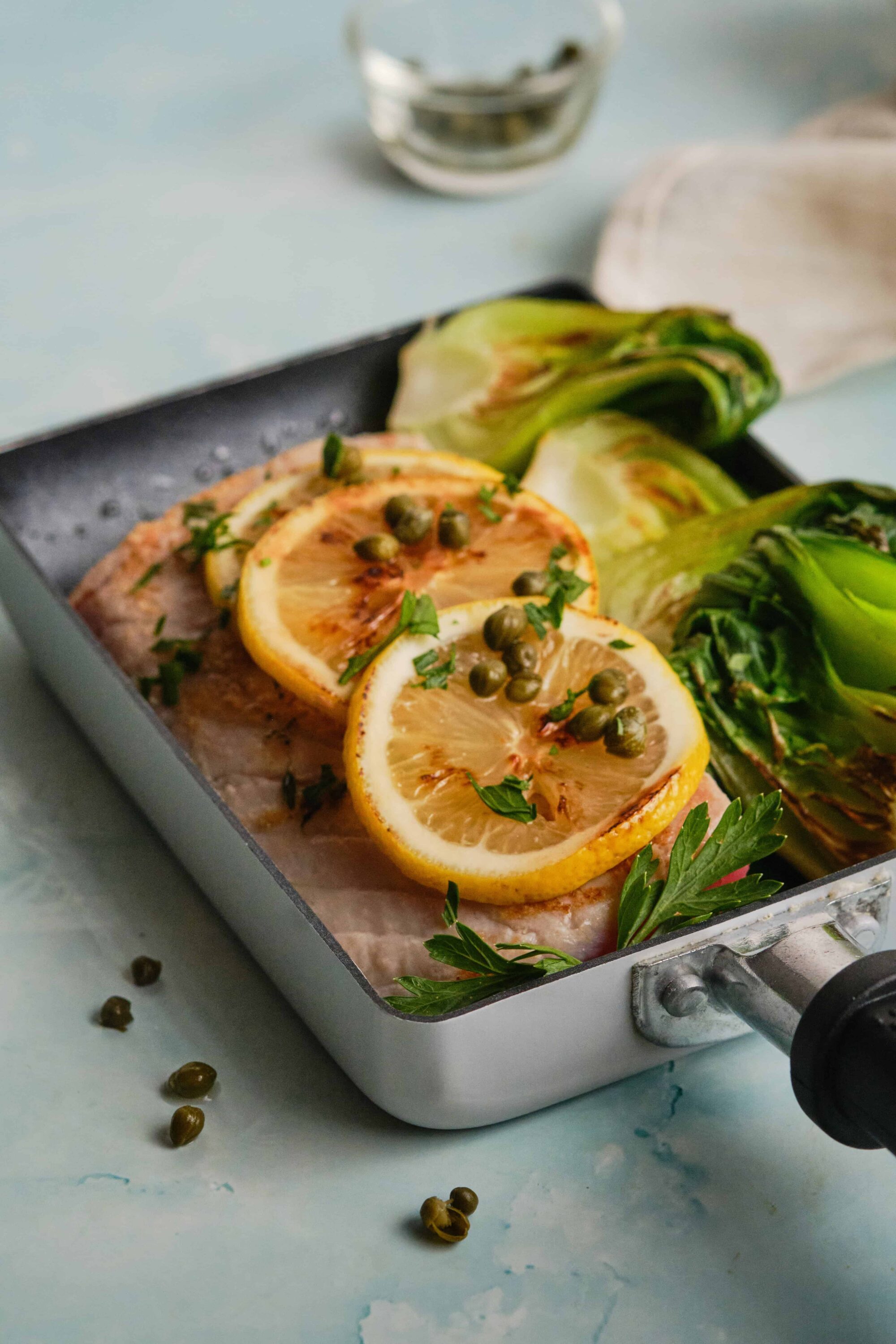 Golden baked fish topped with lemon slices and capers, served with roasted Brussels sprouts. Ideal healthy dinner recipe from Baked Bree.