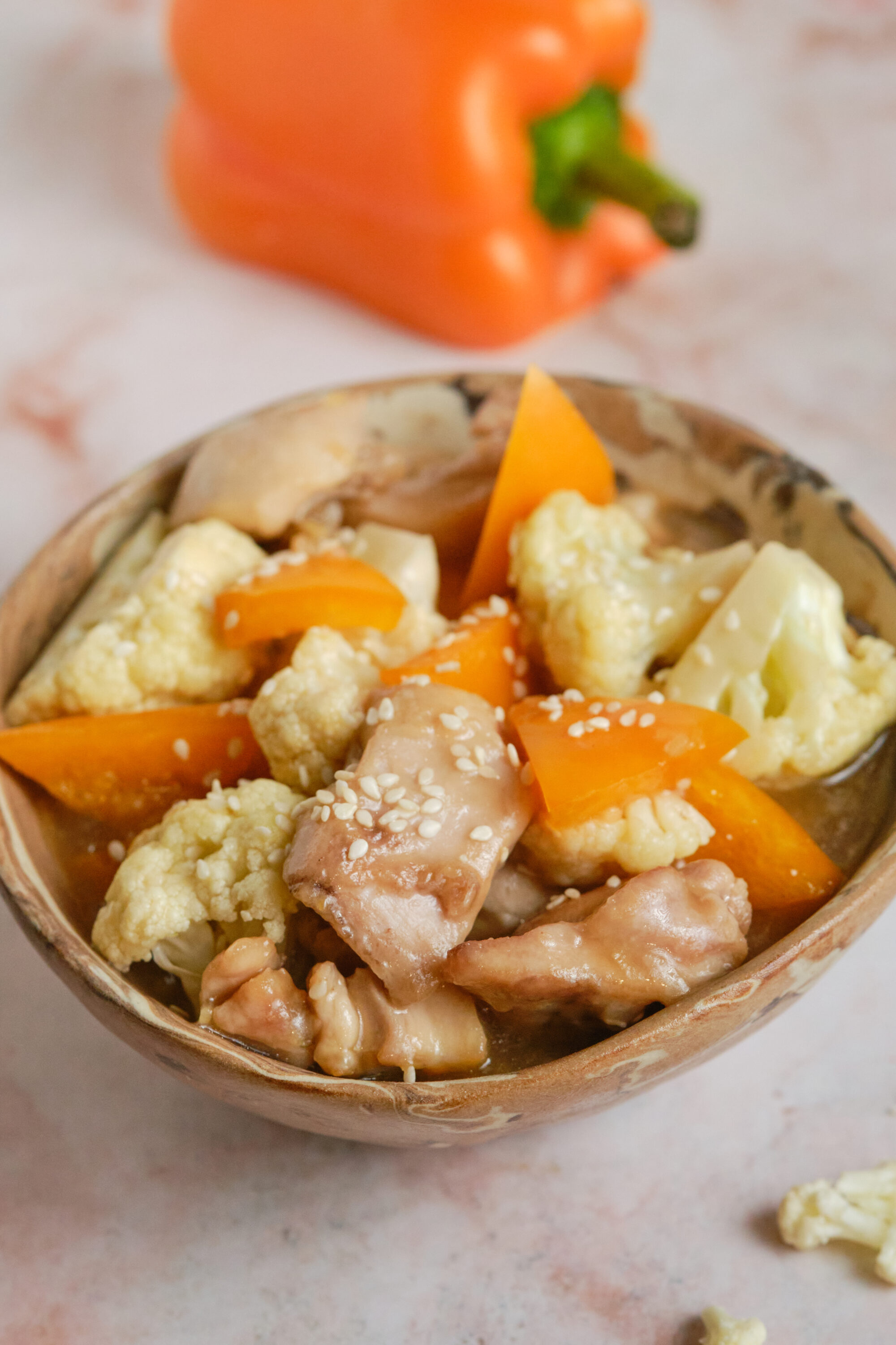 Savory chicken and vegetable cauliflower rice in a rustic bowl, featuring cauliflower, chicken, and colorful peppers.