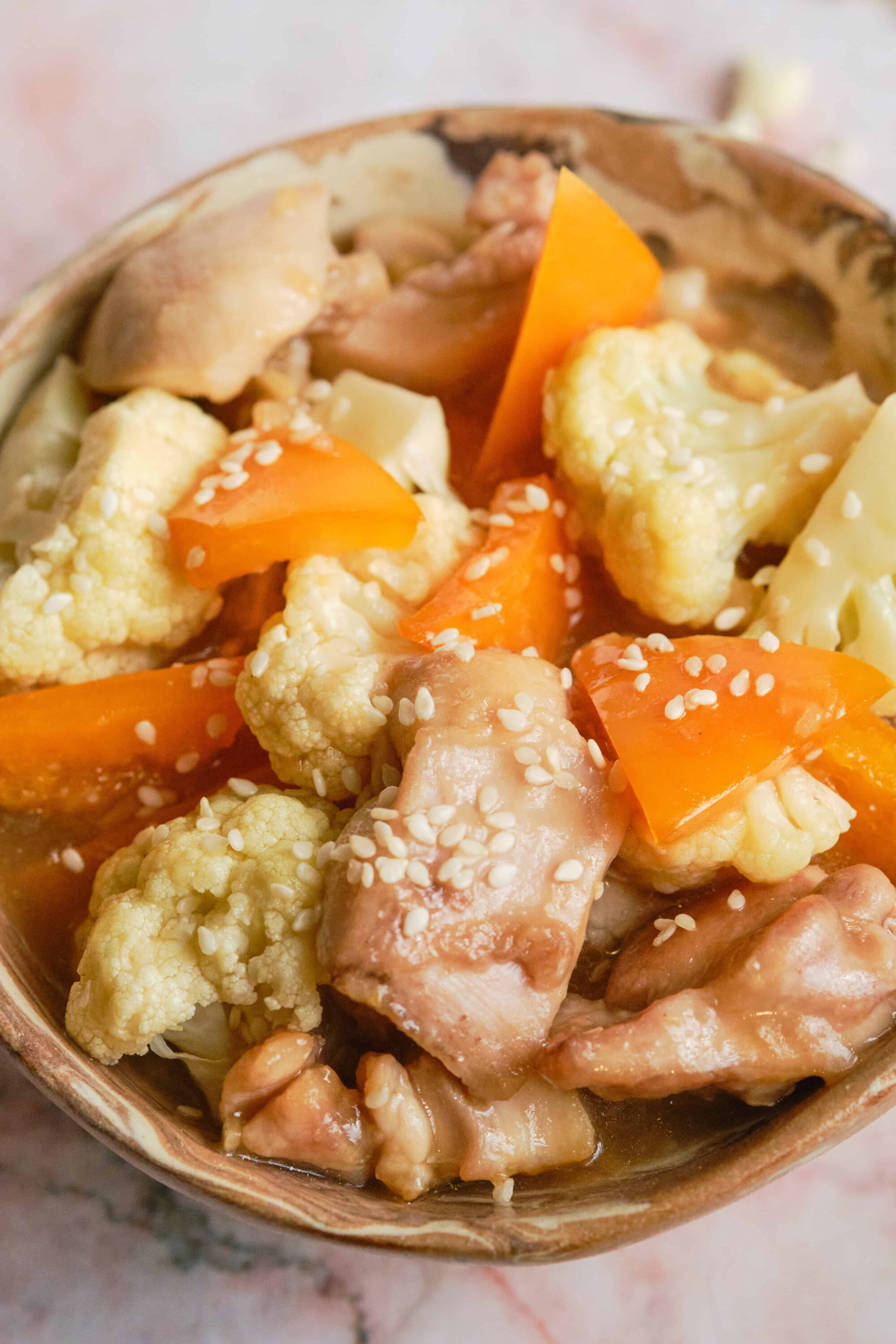 Savory chicken and vegetable stew with cauliflower, carrots, and cauliflower served in a rustic bowl.