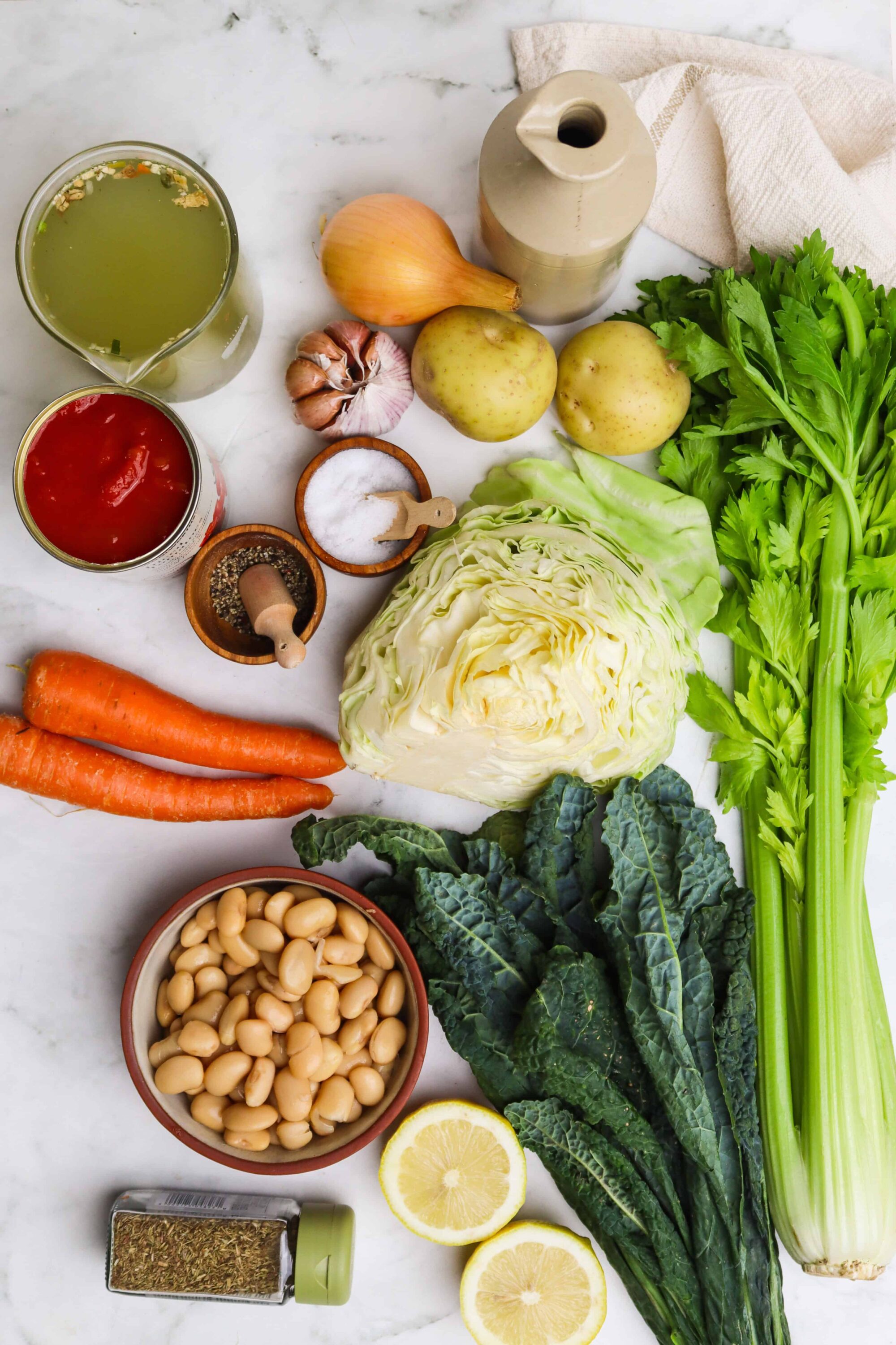 Fresh vegetable ingredients for cooking, including carrots, cabbage, celery, potatoes, onion, garlic, and canned tomatoes.
