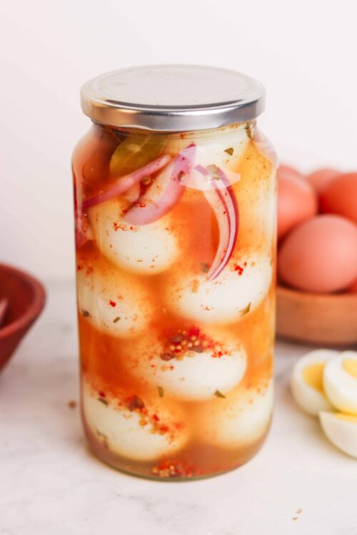 Pickled quail eggs in a jar with red onion and spices, homemade preserved eggs for snacks or cooking.