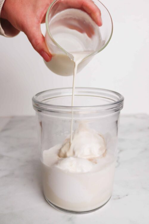 Cream being poured into a jar of whipped cream for baking or dessert recipes, highlighting baking techniques and ingredients.