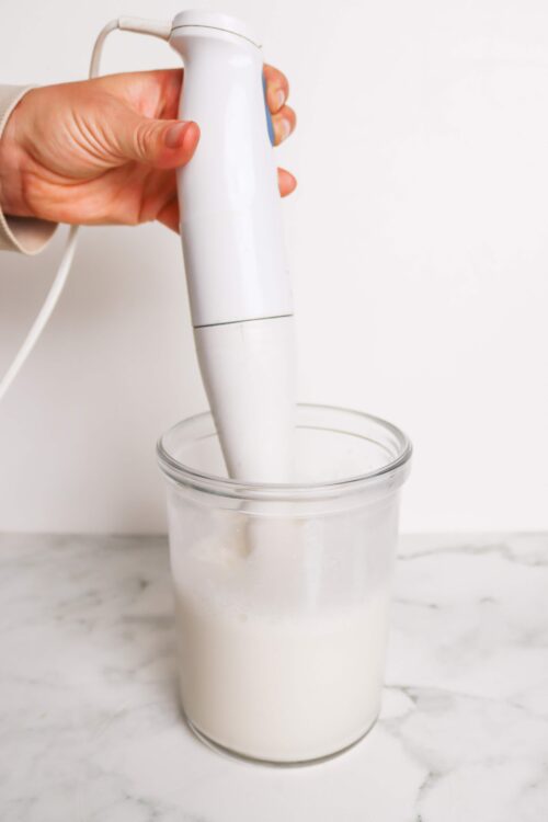 Whisking milk with an electric hand blender for baking recipes.