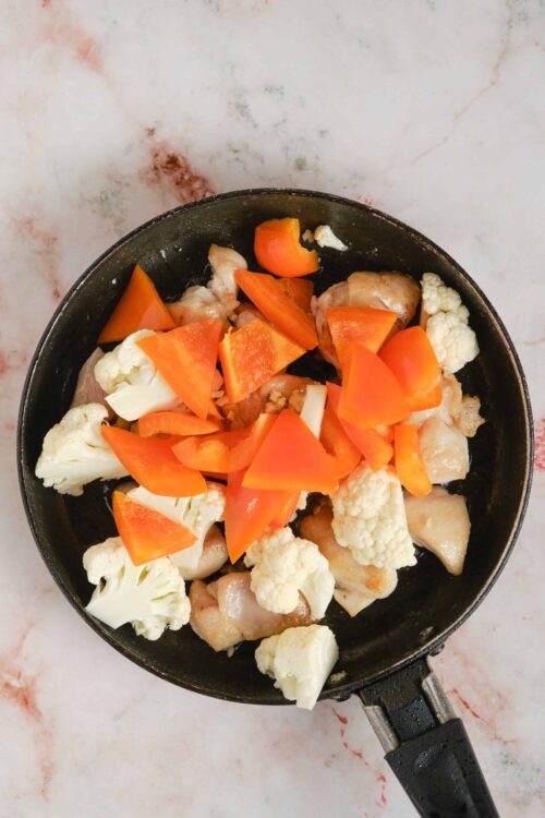 Softened cauliflower, carrots, and chicken in a skillet for healthy meal prep or stir-fry.